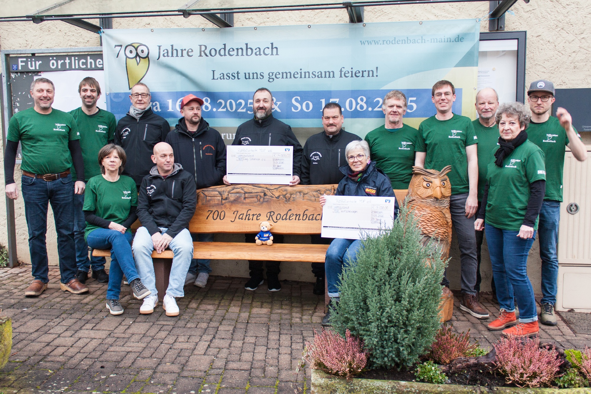 Spendenübergabe in Rodenbach mit 14 PErsonen, vor und hinter einer Bank mit der Aufschrift 700 JAhre Rodenbach